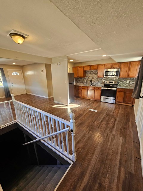 A kitchen with wooden floors and a staircase.