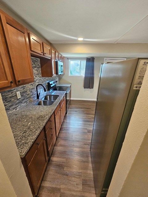 A kitchen with wooden cabinets and a granite countertop.