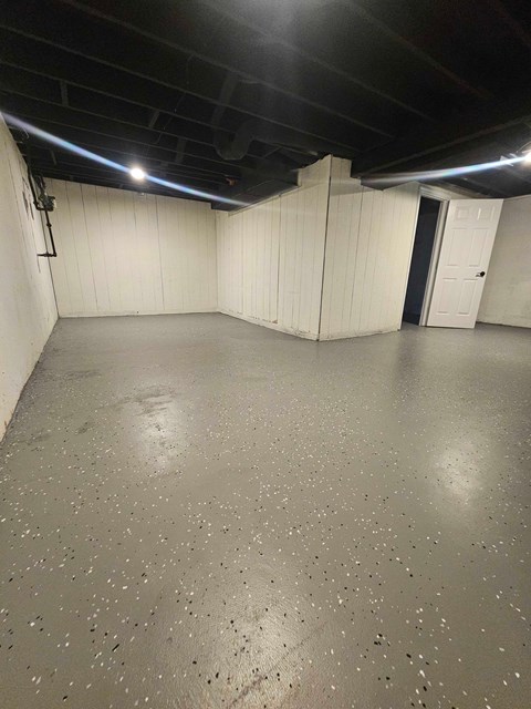 A spacious room with a concrete floor and white walls.