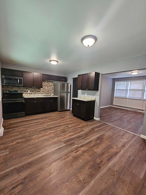 A kitchen with wooden floors and a stone backsplash.