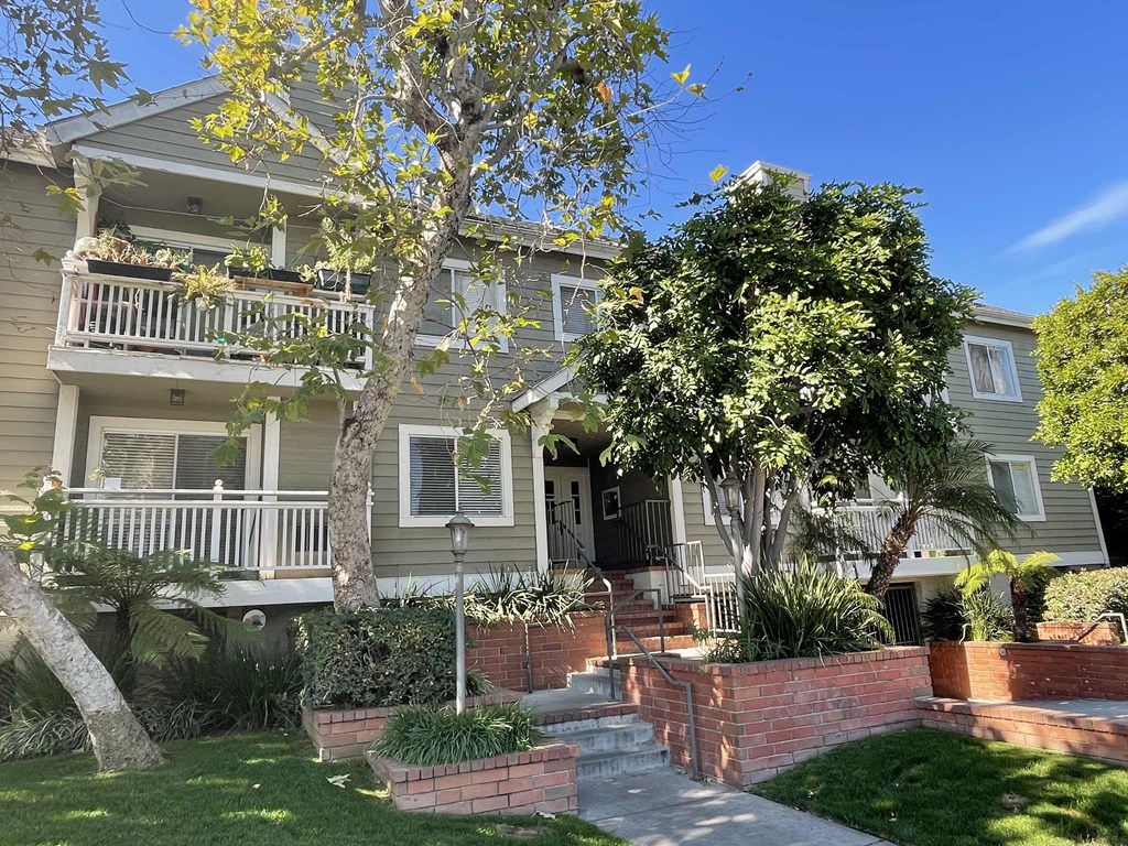 an old house with a porch and a tree in front of it