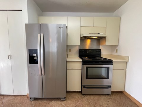 A stainless steel refrigerator and oven in a kitchen.