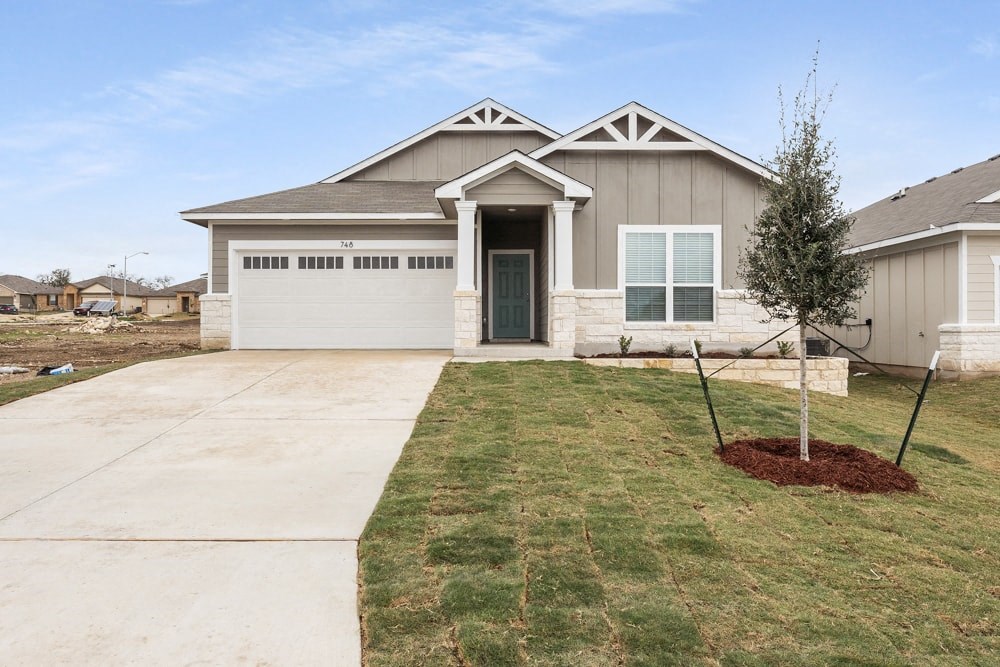 the front of a house with a driveway and a tree