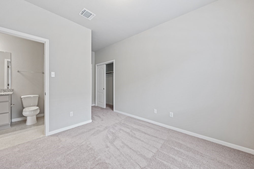 an empty bedroom with a bathroom and a toilet