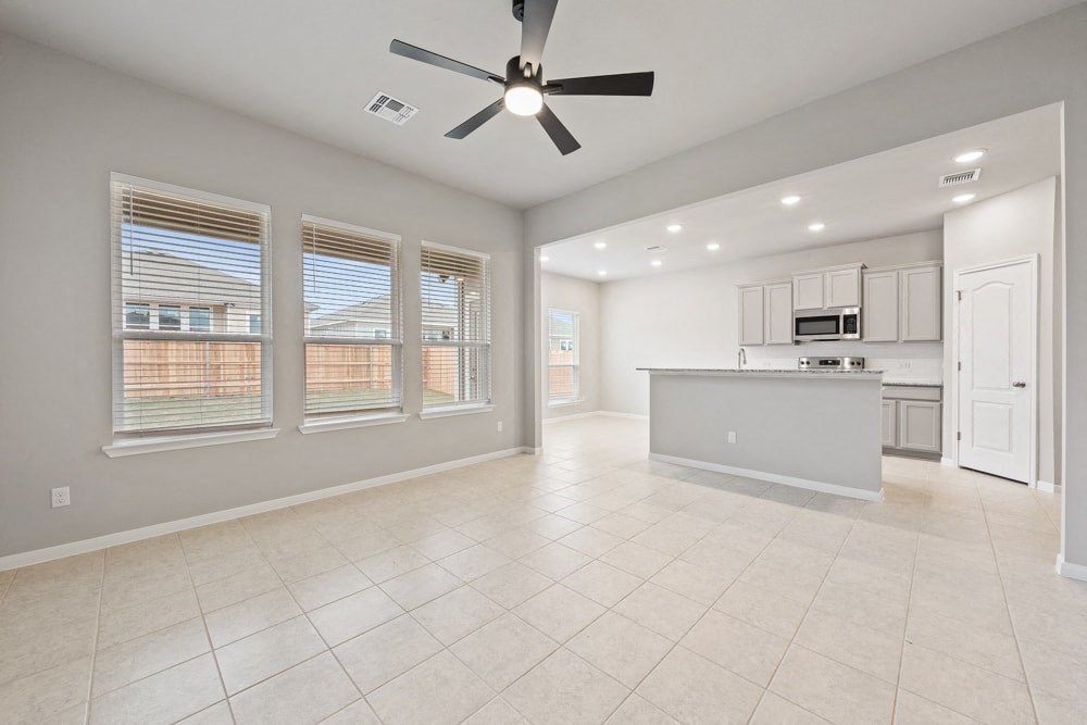 an empty kitchen and living room with a ceiling fan