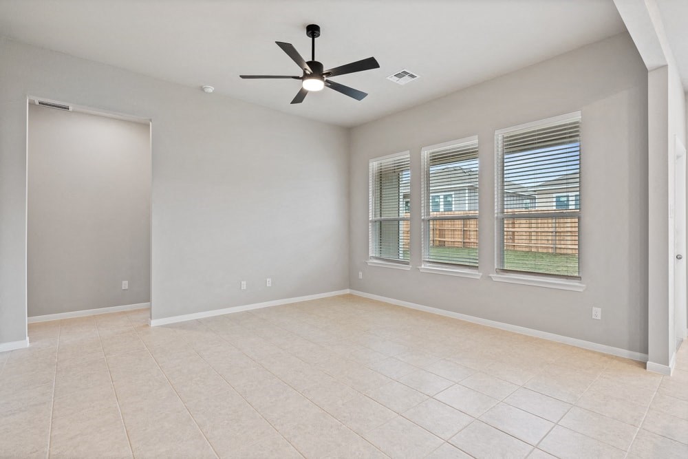 an empty living room with a ceiling fan and a window