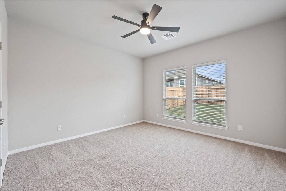 an empty living room with a ceiling fan and a window