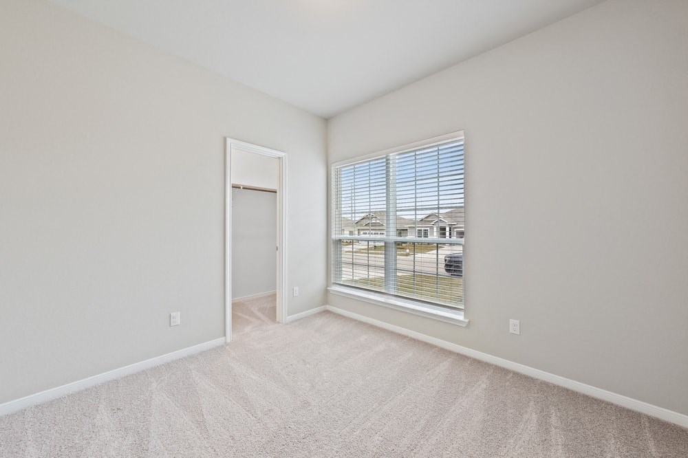 an empty living room with a large window and a door