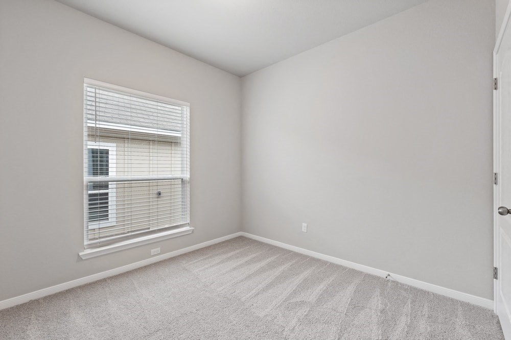 an empty bedroom with a large window and carpeting