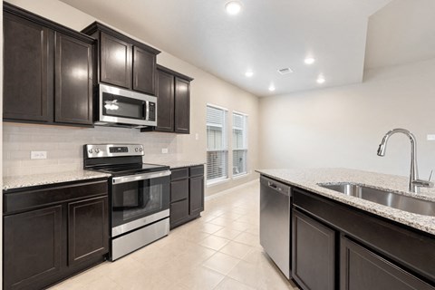 a kitchen with black cabinets and stainless steel appliances