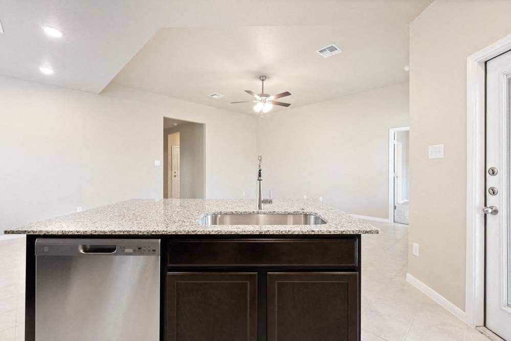 an empty kitchen with a sink and a ceiling fan