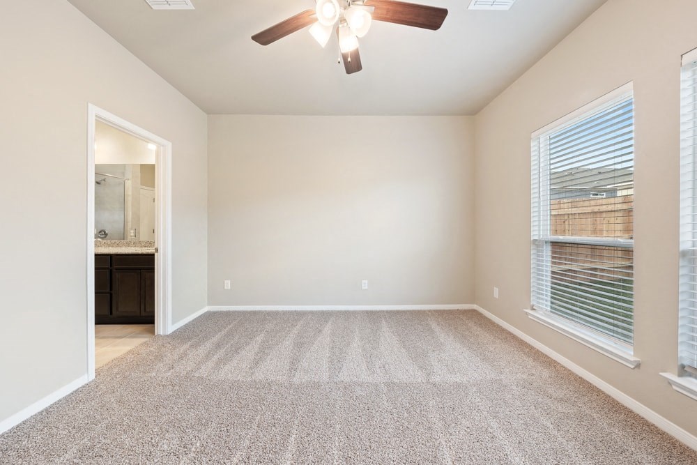 an empty living room with a ceiling fan and a window