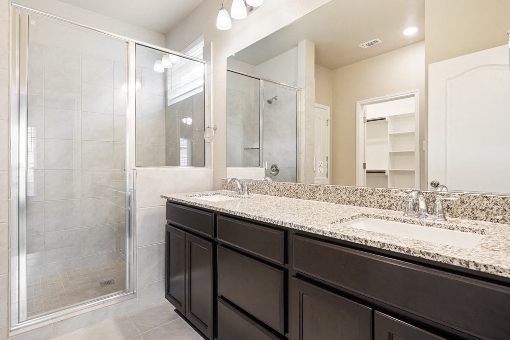 a bathroom with two sinks and a shower