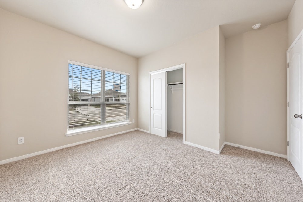 an empty living room with a large window and carpet