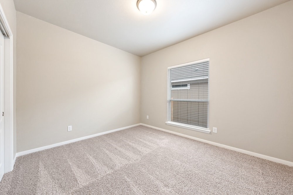 an empty living room with a window and carpet