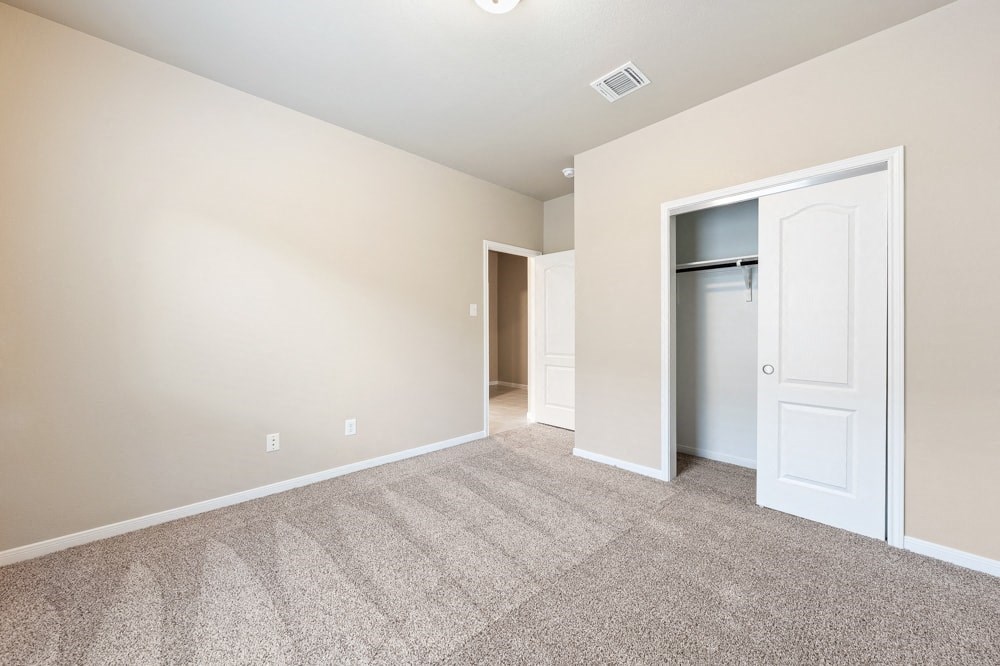 an empty living room with an open door to a closet