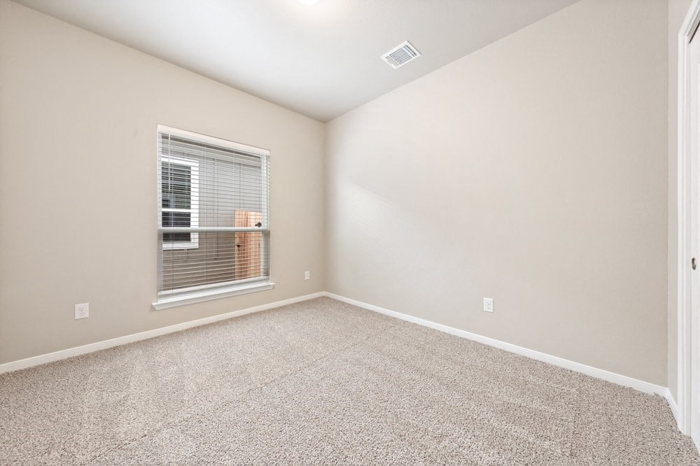 an empty living room with a window and carpet