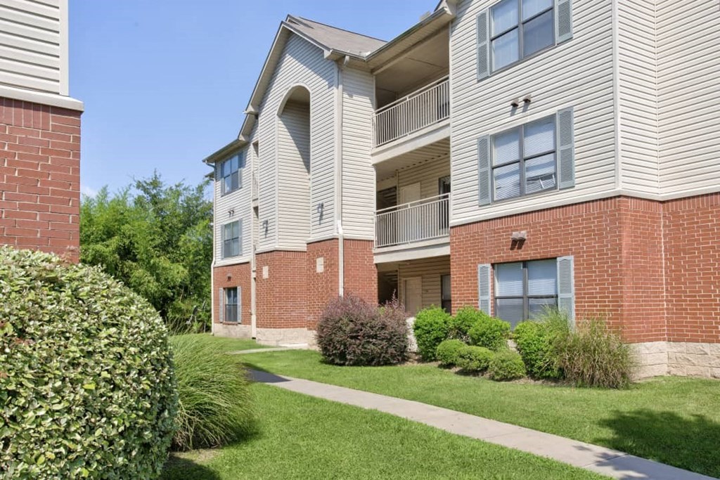 A building with a balcony and a green lawn in front.