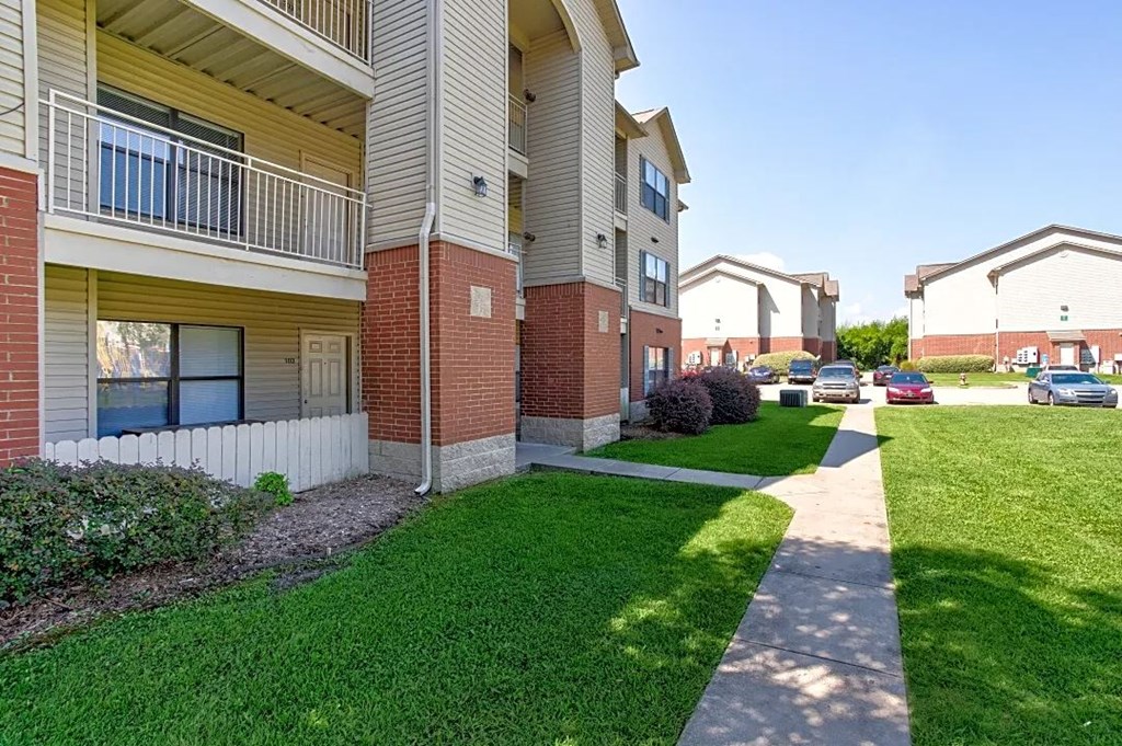 A sunny day at a residential apartment complex with green lawns and a clear blue sky.