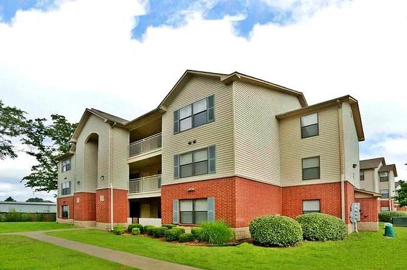 Apartment building with a red brick facade and a green lawn in front.