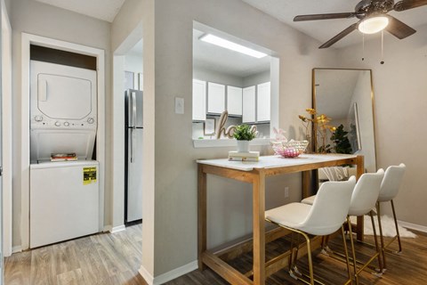 A kitchen with a white fridge and a dining table with chairs.