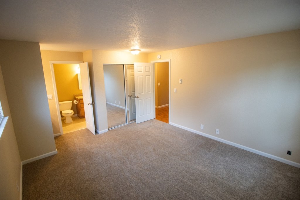 an empty living room with a bathroom and a closet