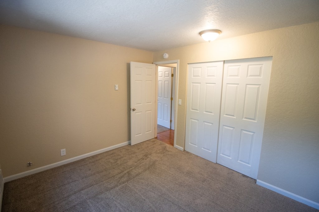 a empty living room with two doors and a carpeted floor