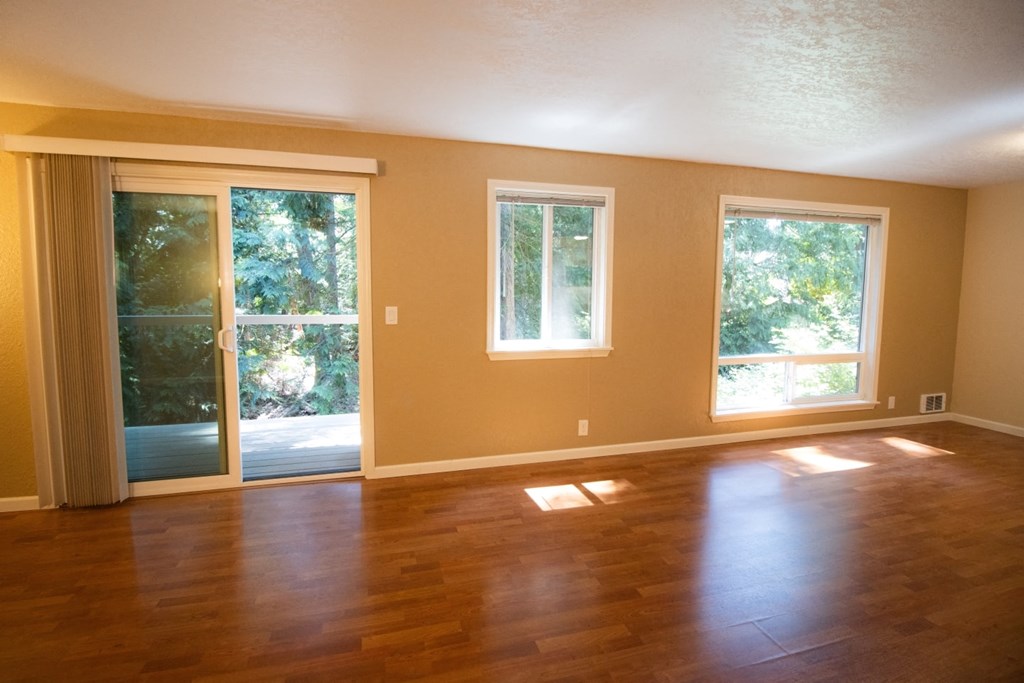 an empty living room with a hard wood floor and sliding glass doors
