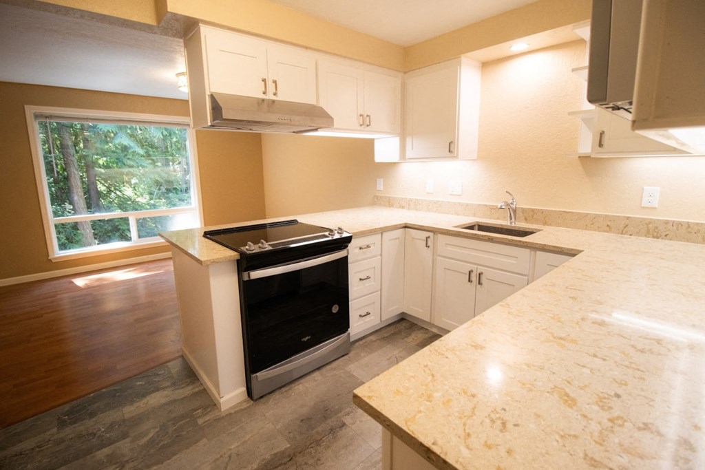 a kitchen with white cabinets and a stove and a window