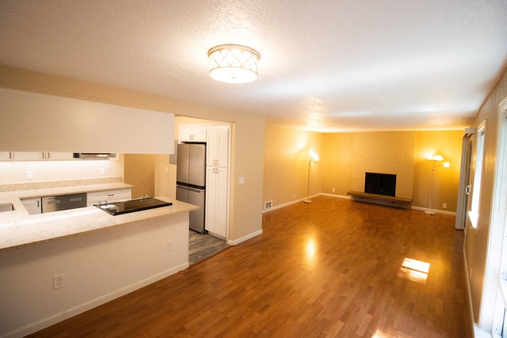 an empty living room and kitchen with a hard wood floor
