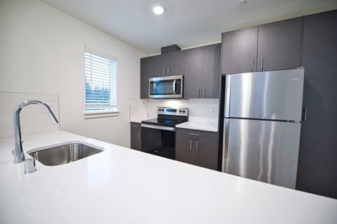 a kitchen with a white counter top and a stainless steel refrigerator