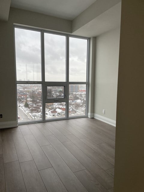 an empty living room with large windows and wooden floors