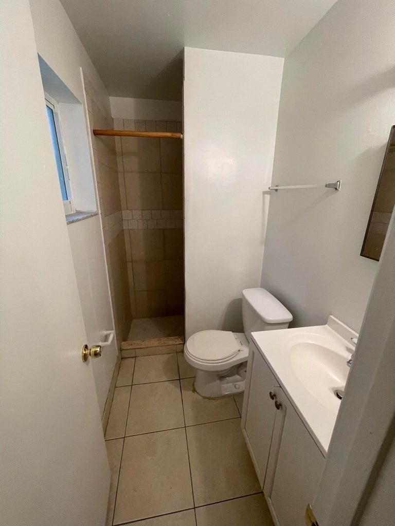 A white bathroom with a toilet, sink, and shower.