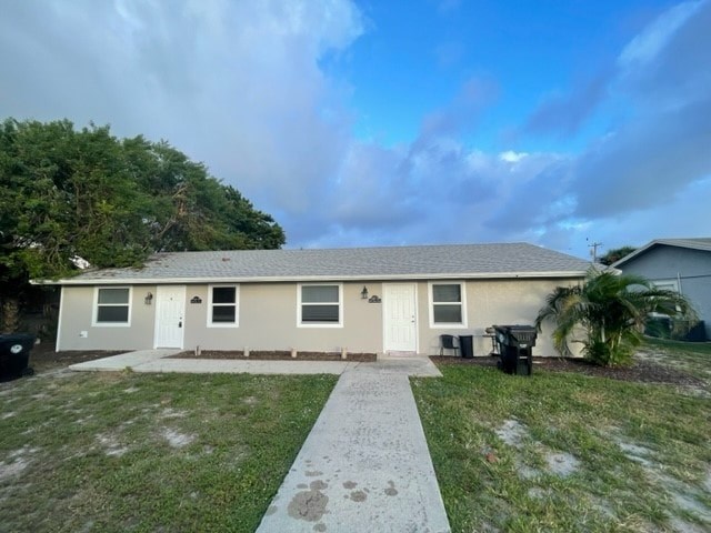 A house with a white door and windows is surrounded by a grassy area and trees.