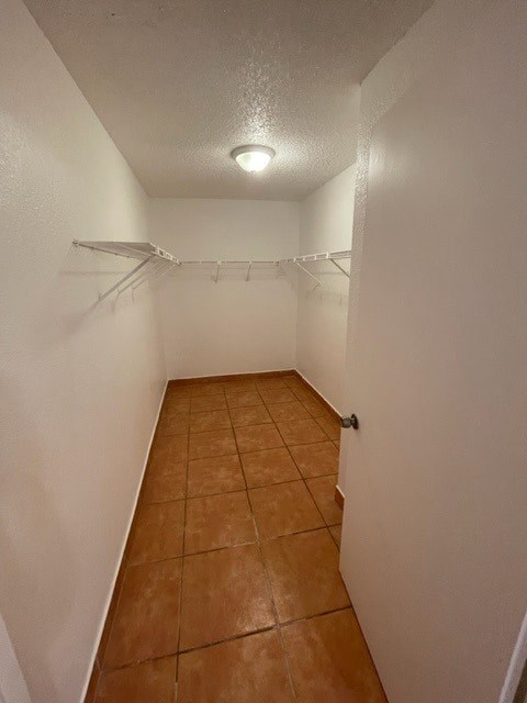 A long, narrow hallway with a tiled floor and white walls.