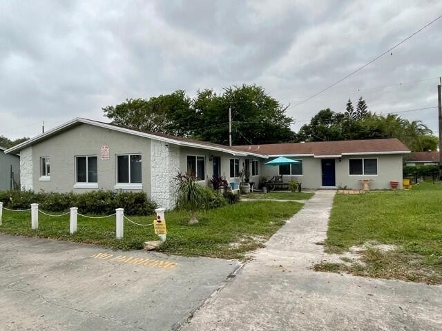 A white building with a green awning is surrounded by a chain link fence.