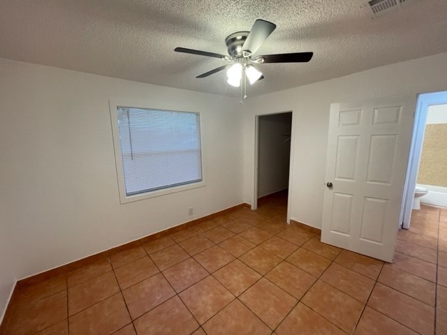 A room with a ceiling fan and tile flooring.