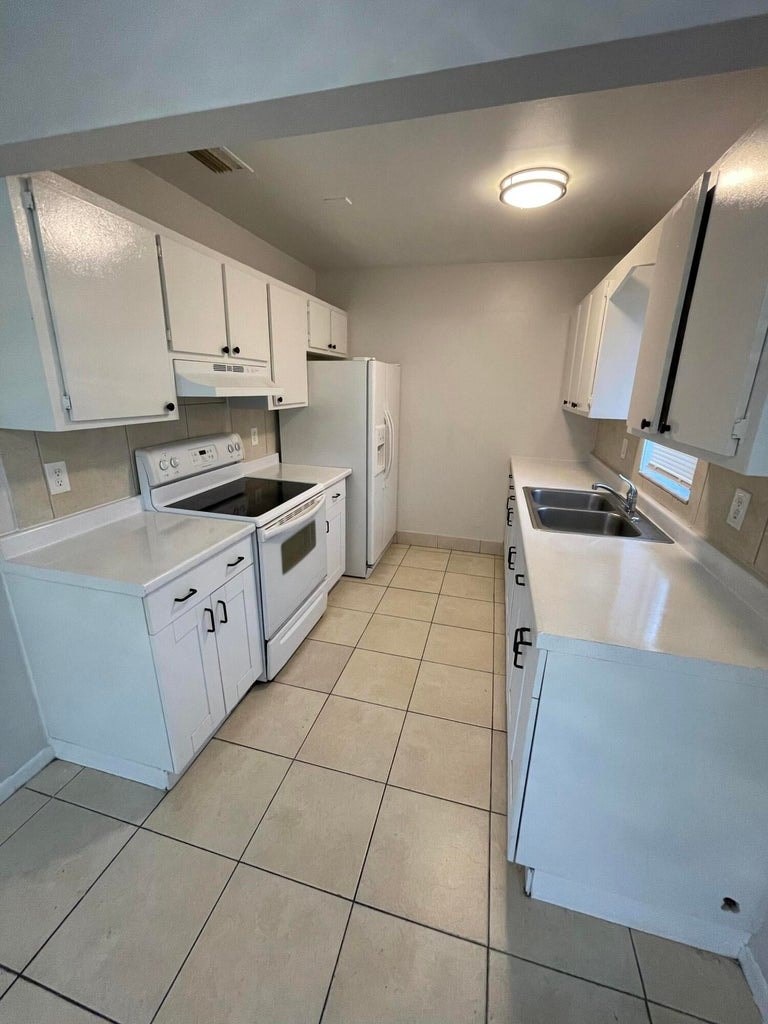 A kitchen with white cabinets and appliances.