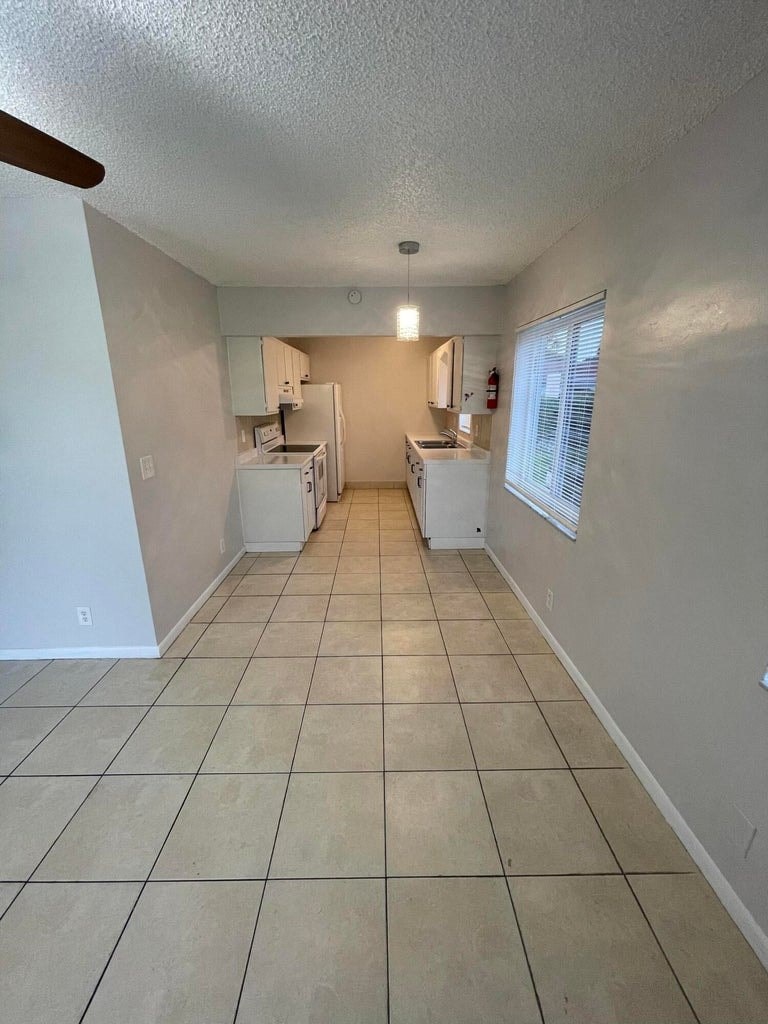 A kitchen area with white appliances and tiled flooring.