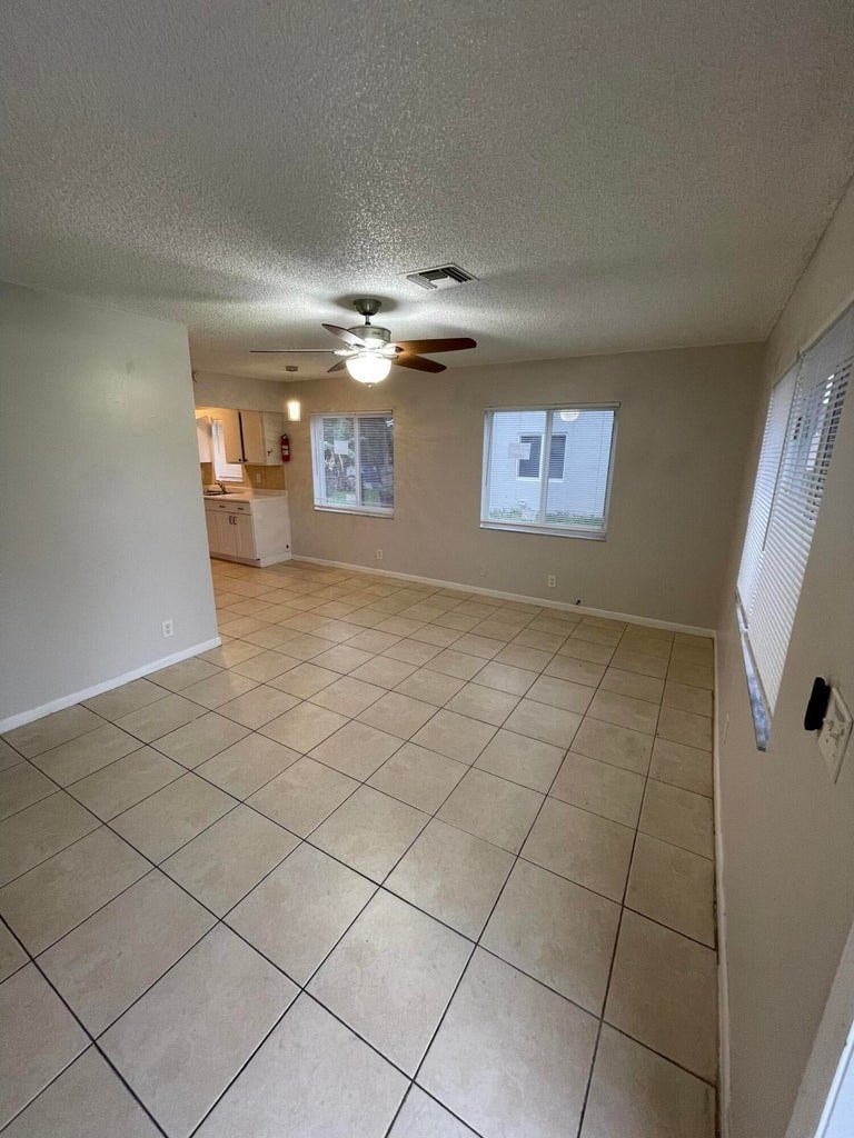 A room with a ceiling fan and tile flooring.