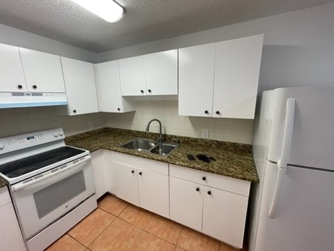 A kitchen with white cabinets and a granite countertop.