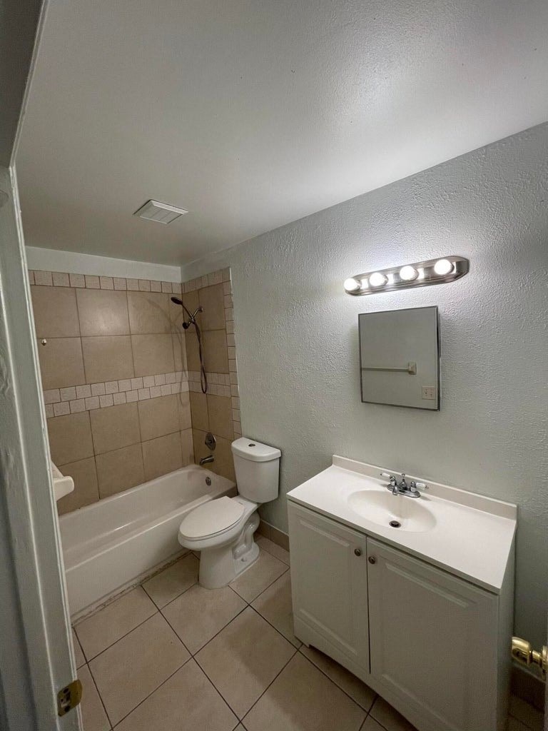 A bathroom with a toilet, sink, and mirror.