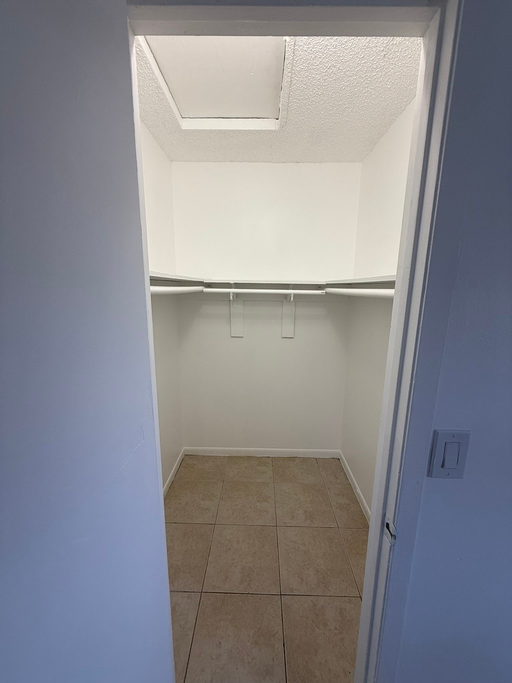 A small, empty room with a white ceiling and a door on the right.