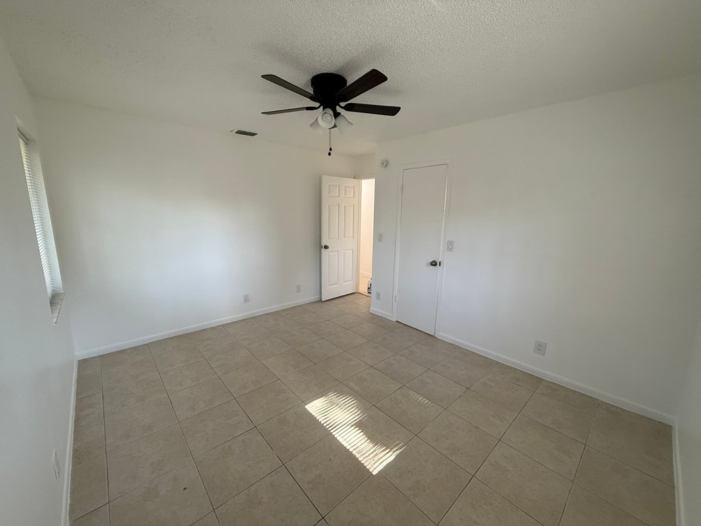 A room with a ceiling fan and tile flooring.