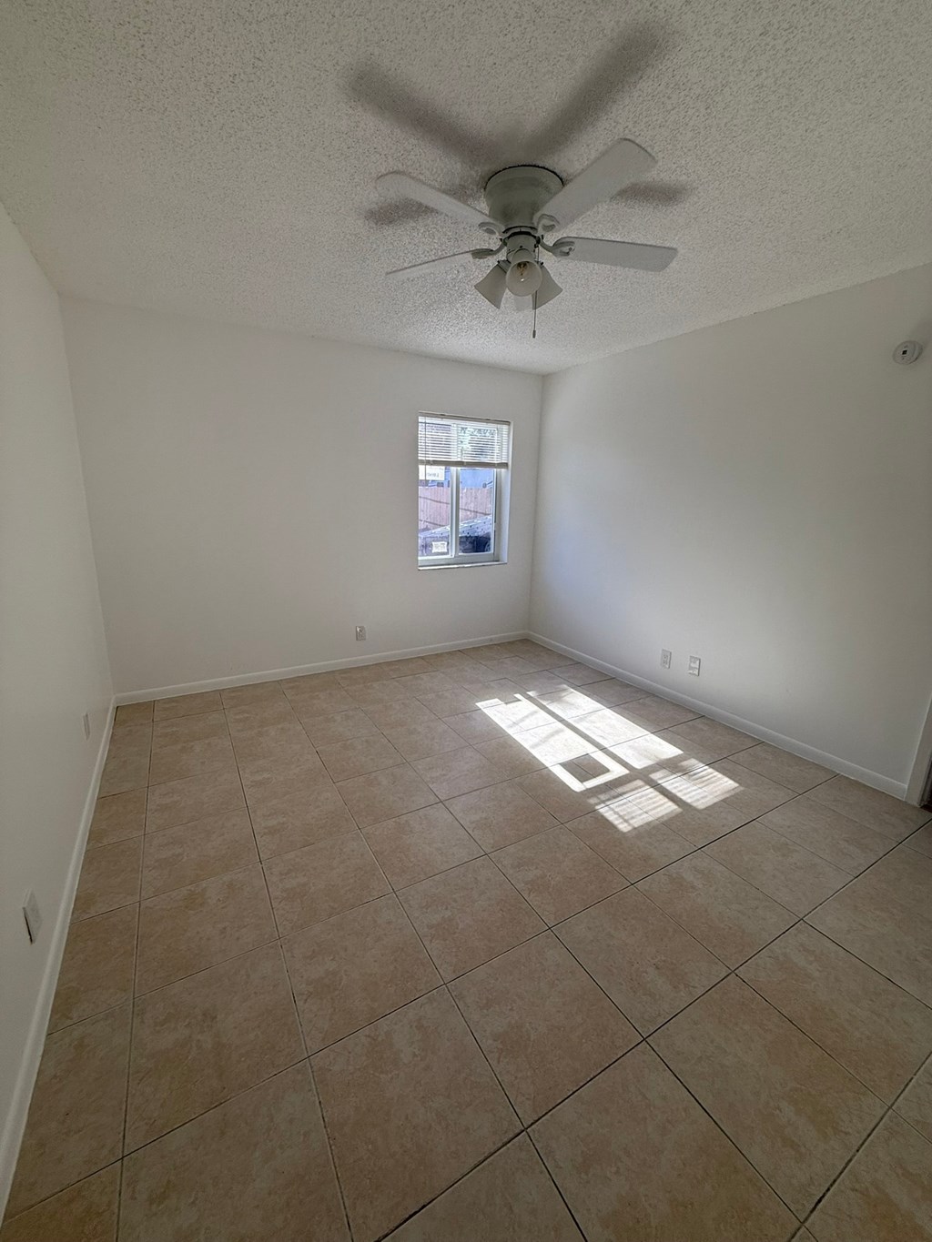 A room with a ceiling fan and a window.
