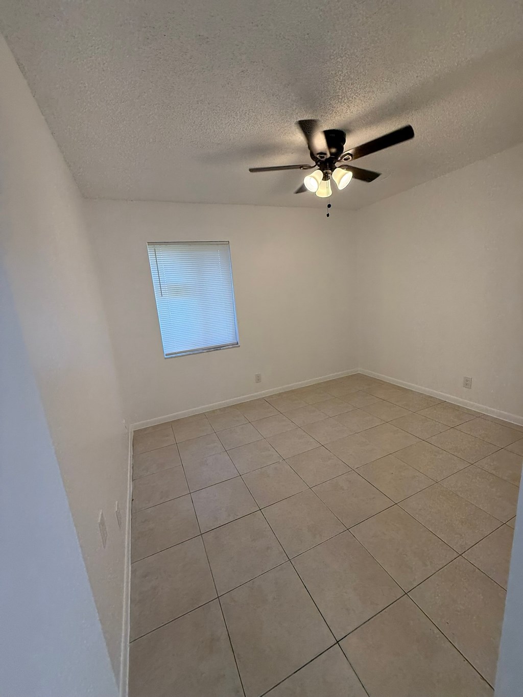 A room with a ceiling fan and a window.