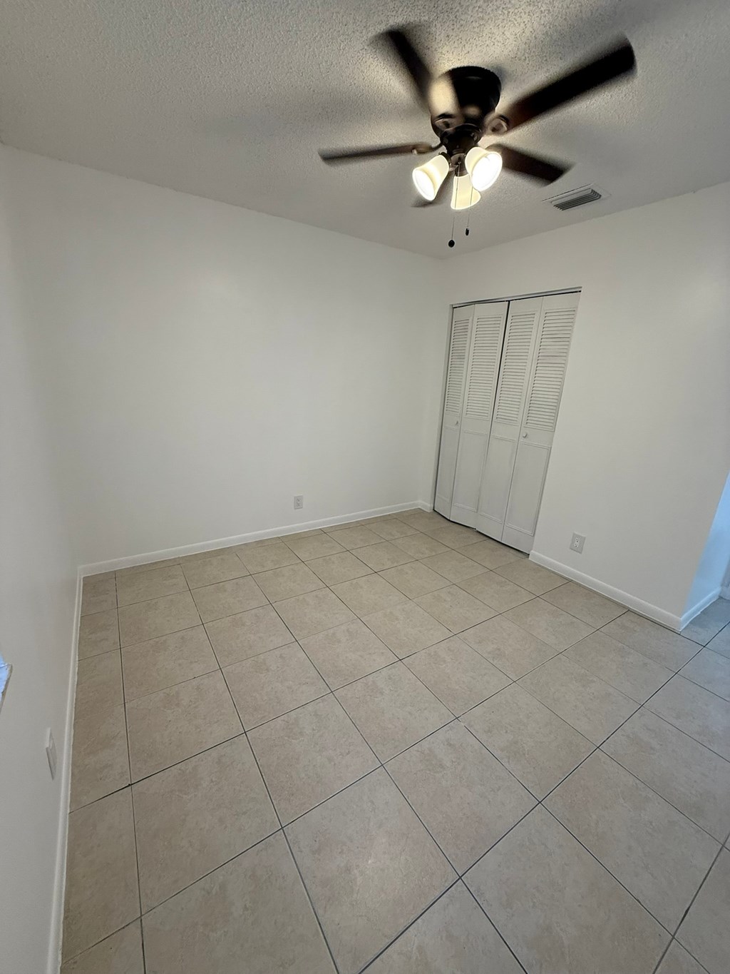 A room with a ceiling fan and tile flooring.
