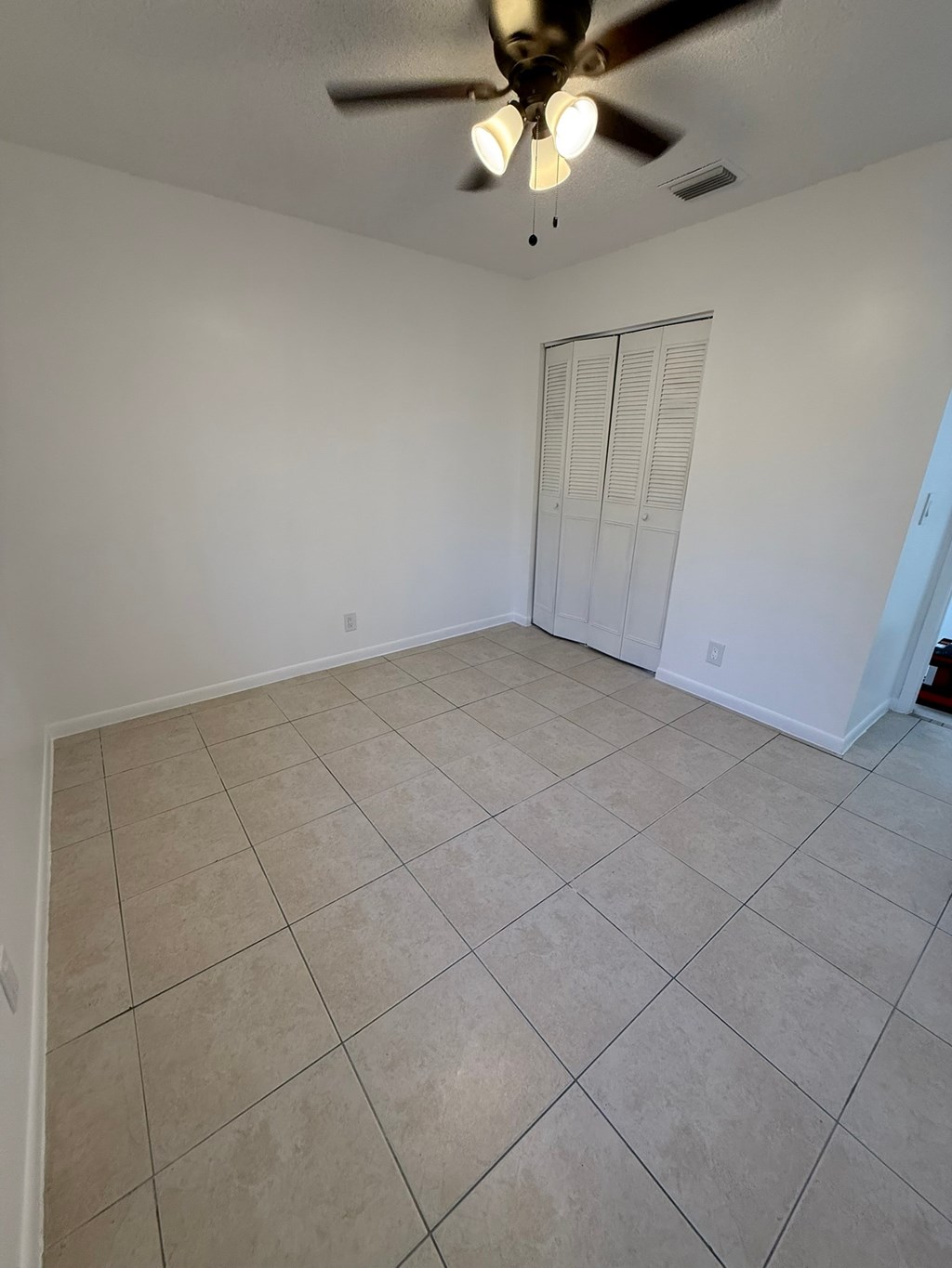 A room with a ceiling fan and tile flooring.