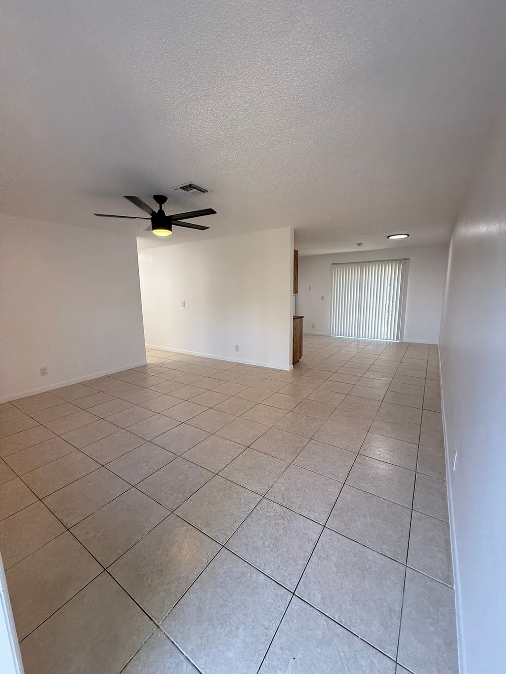 A room with a ceiling fan and tiled flooring.