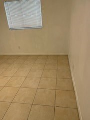 A room with a tiled floor and a window with blinds.